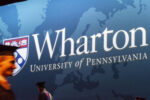 Banner featuring the Wharton School, University of Pennsylvania logo, with blurred figures in graduation attire walking by.