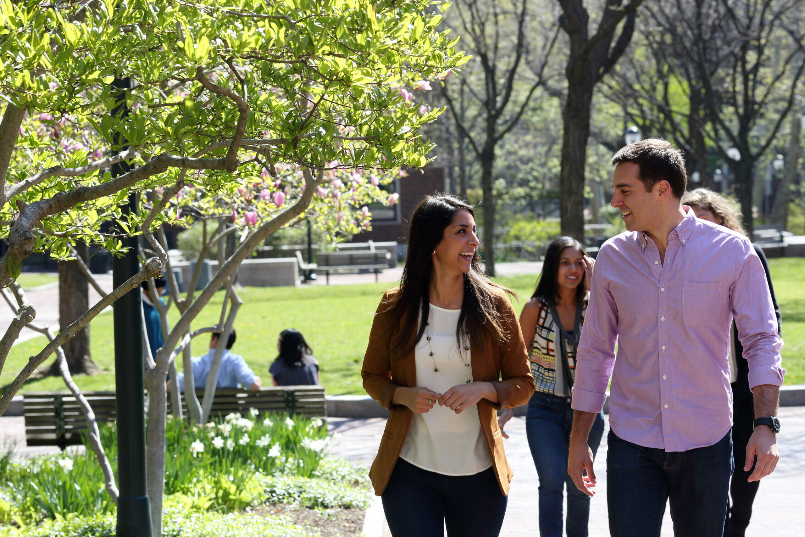 Students smiling and talking as they walk outside on Penn's campus during the spring time