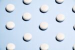 White round pills arranged in diagonal rows on a light blue surface