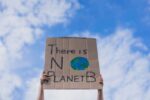 Stock image of hands holding a handmade sign up that says "There is NO Planet B" against a cloudy blue sky