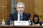 Dr. Benjamin keys testifying before the US Senate Committee on the Budget in a suit and tie.