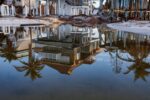 Reflection of beachside homes in shallow water on sandy shore