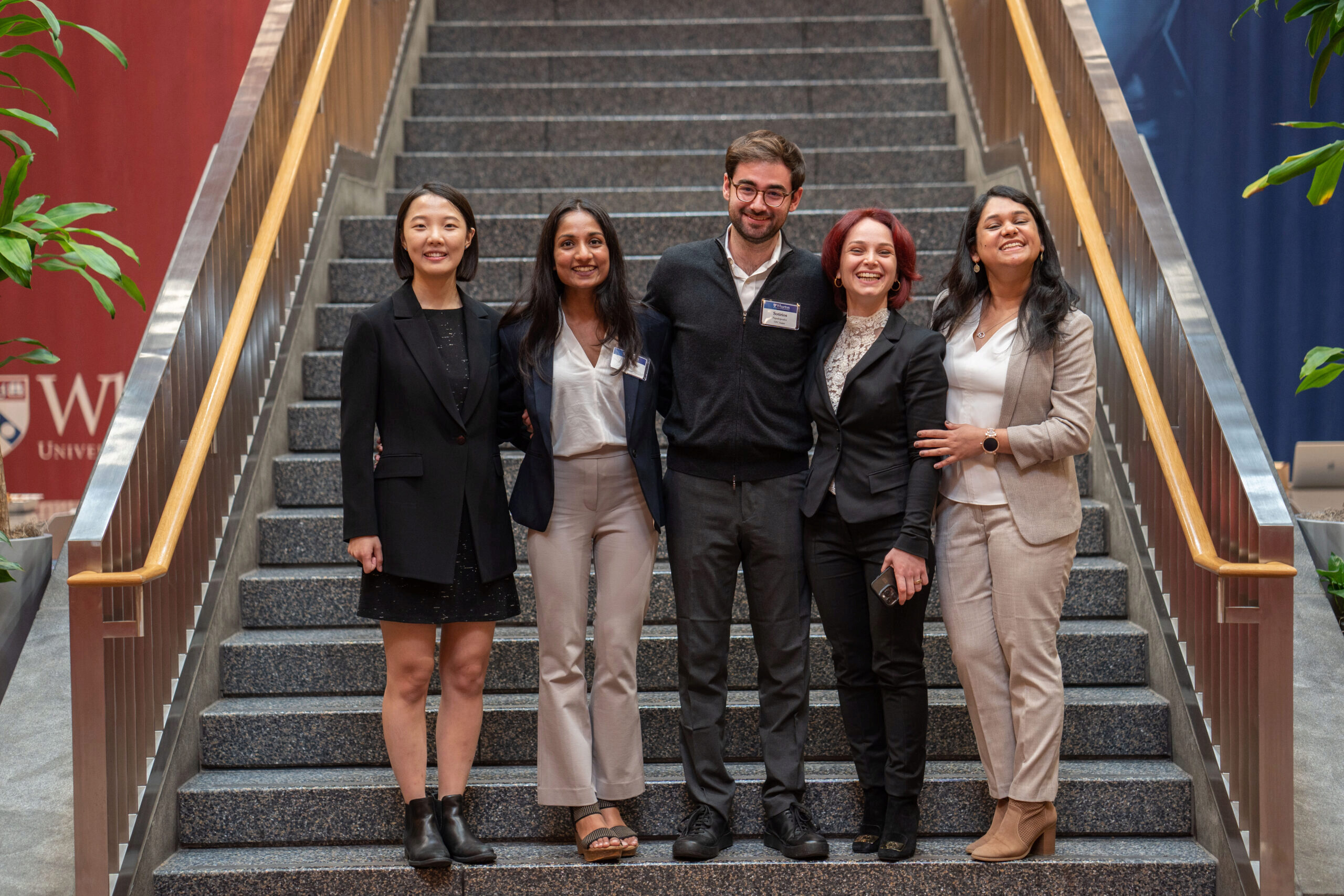 Image of the 5 members of the winning The Fletcher School, Tufts University team on the stairs of Huntsman Hall.