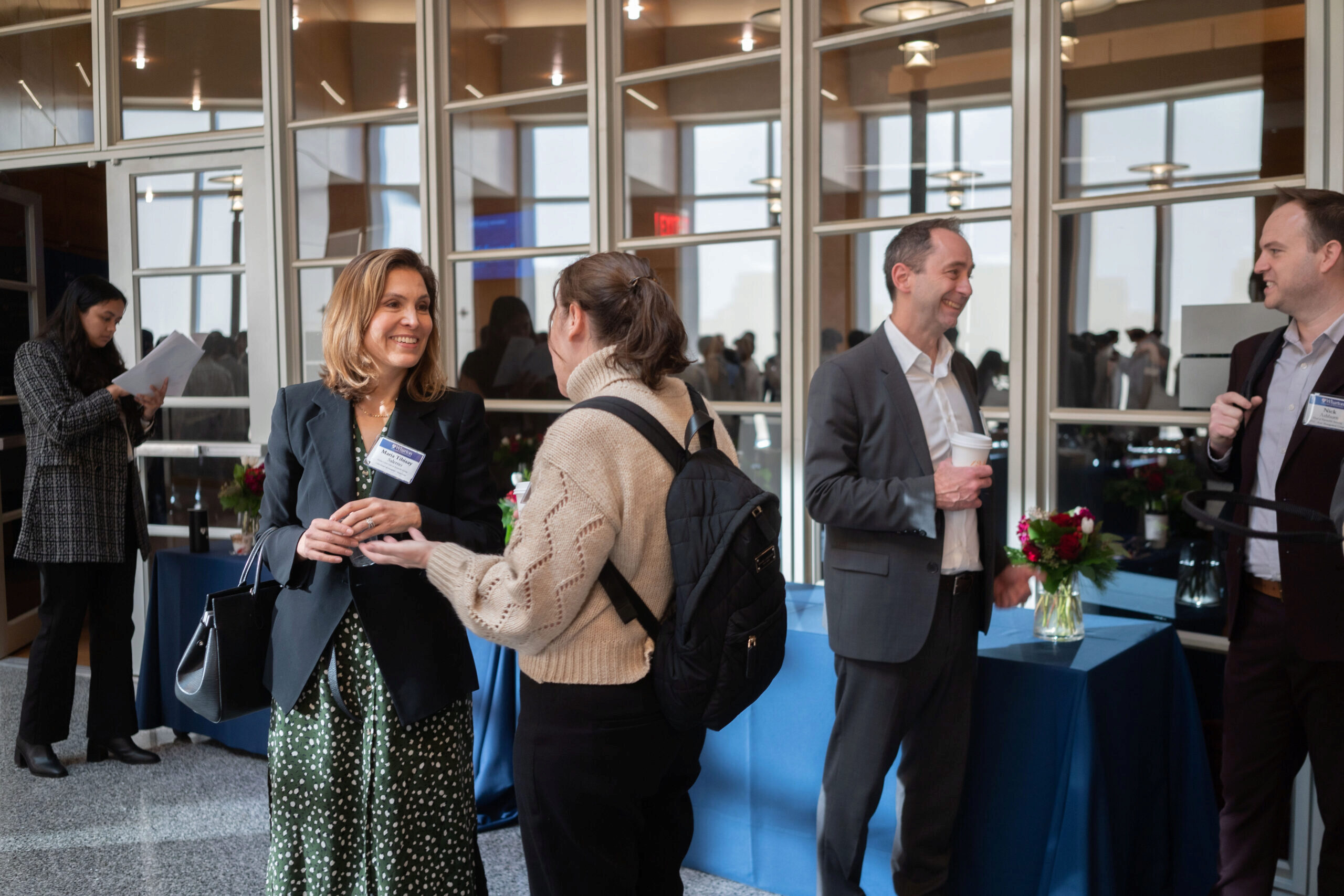 People in business attire networking at the breakfast reception in a bright room with blue tablecloths