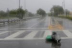 A blurry wet crosswalk with debris from storms.