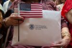 Hands hold an American flag and an envelope that reads US Citizenship and Immigration services.