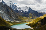Stock image of the andes mountains in Peru with snow at their caps and green land at the bottom near a bright blue lake