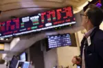 A man gazes up at a tv screen on the stock floor.