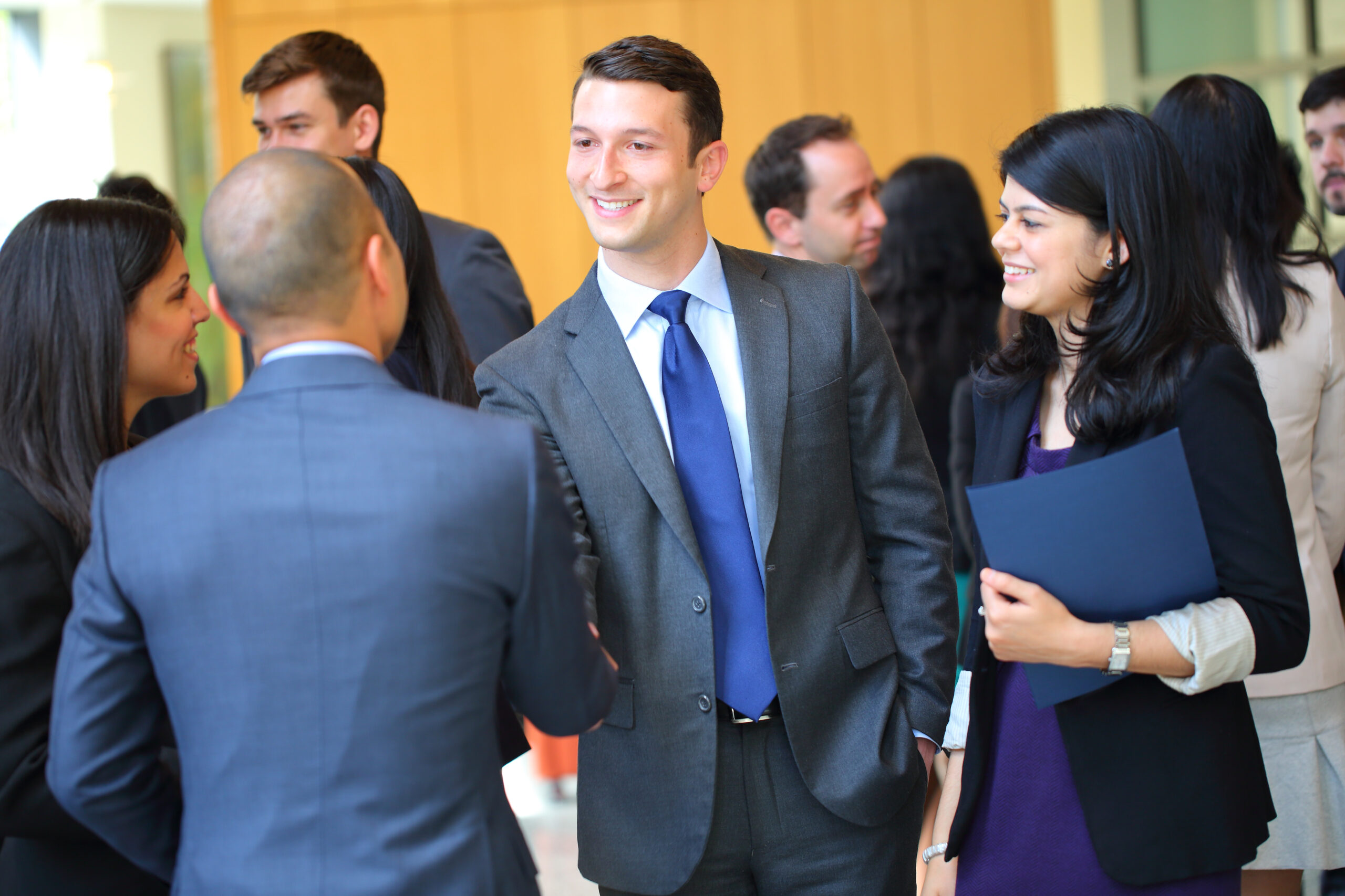 Wharton students in business professional attire shake hands with a recruiter at a career fair.
