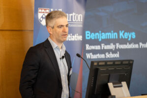 Benjamin Keys speaks at a podium in front of a slide that reads "Benjamin Keys Rowan Family Professor Foundation Wharton School"